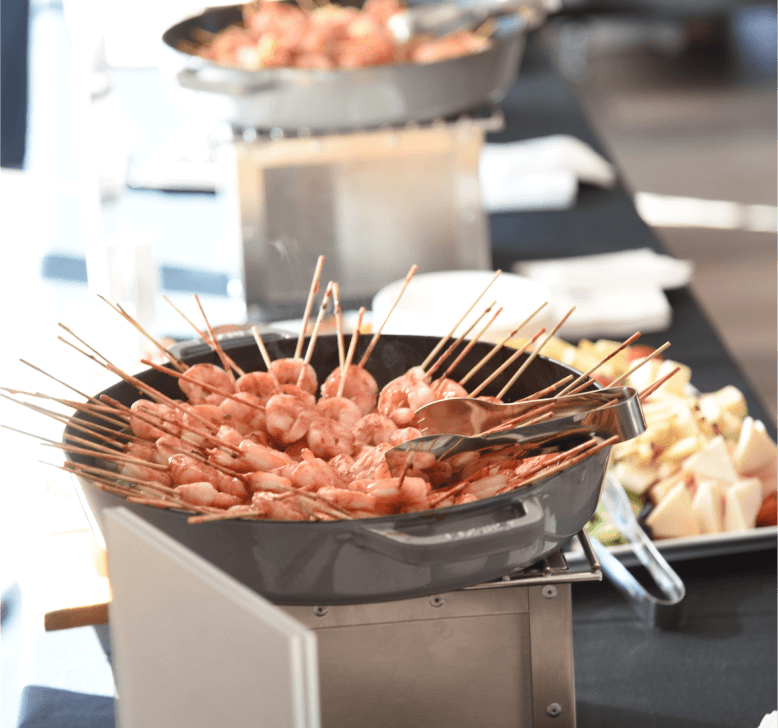Guests laughing and socializing around red tablecloth cocktail tables with bowls of strawberries at a networking event.
